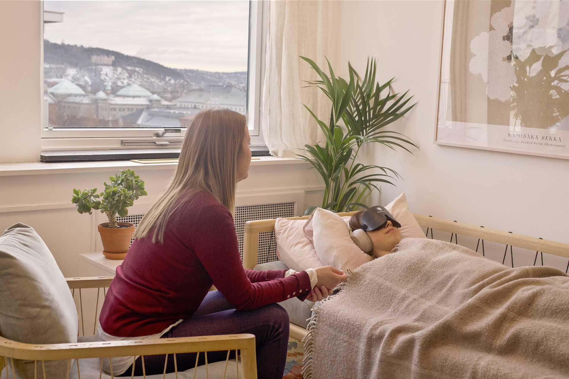 Behandlingsrom hos EmmaSofia med utsikt over fjorden. En behandler sitter ved siden av en pasient som hviler.